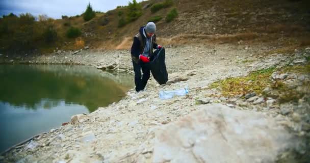 운동가가 호숫가의 쓰레기를 모으고 봉사자들은 바닷가에 플라스틱 쓰레기를 모은다 정화의 — 비디오