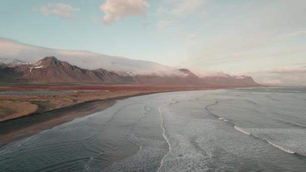 在海浪冲破冰岛海岸的上空缓慢地盘旋 背景中的山脉 — 图库视频影像