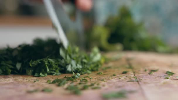 女人的手非常近 在厨房的木板上用一把意大利锋利的切刀慢慢地切碎绿色的欧芹 家庭烹饪和健康食品概念 — 图库视频影像