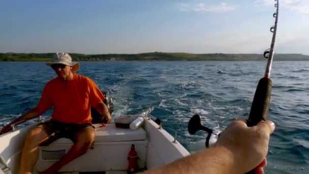 ロッドと背景にモーターボートを移動するステアリングティラーを保持しながら 行に別の漁師のトロール釣りと人間釣りの一人称のPov スローモーション — ストック動画