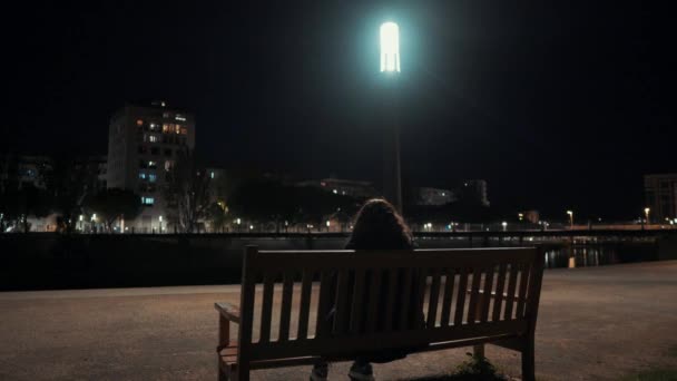 Uma Menina Está Sentada Uma Cadeira Assistindo Cidade Parque Noite — Vídeo de Stock