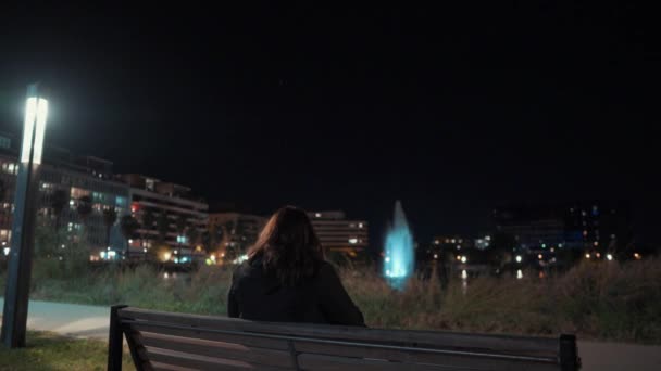 女の子は椅子に座って モンペリエのポート マリアンヌで夜の噴水を見ています フランス — ストック動画