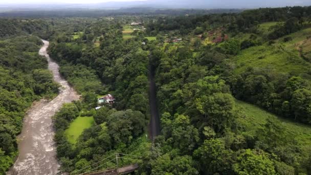 雨季期间 在丛林中中央一座倒塌的钢桥旁边 有4K段下降飞行的航拍镜头 在哥斯达黎加热带雨林中蜿蜒的布朗河 无人机接近道路 — 图库视频影像