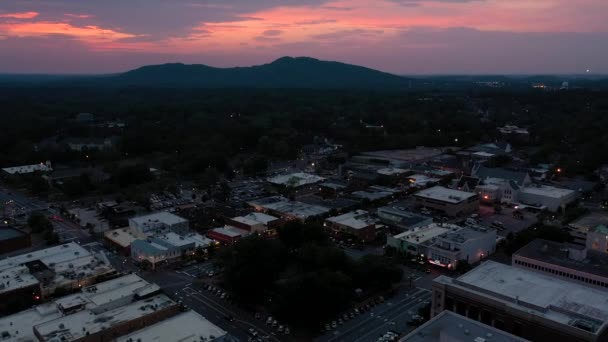 日落时 无人机向地平线上有山的城镇广场飞去 — 图库视频影像