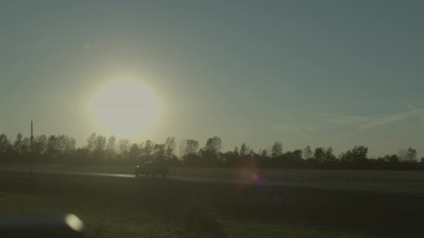 Ein Auto Fährt Bei Sonnenuntergang Eine Landstraße Hinunter Während Die — Stockvideo