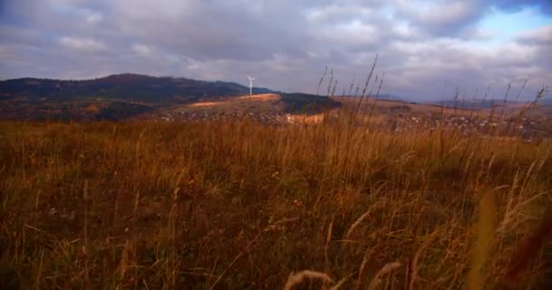スローモーションで曇りの日に風力タービン 山の中で太陽と風車 地球を緑化するという考え方です 背景には秋と黄色の草 — ストック動画