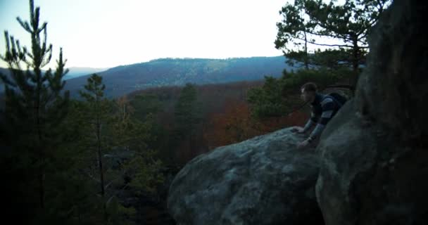 白种人的背景是带着高山和森林爬上岩石 男性游客环视四周 夕阳西下 景色优美 旅行和度假概念 — 图库视频影像