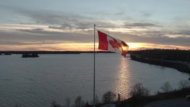 Hermosa Bandera Canadiense Ondeando Atardecer Sobre Agua — Vídeo de stock