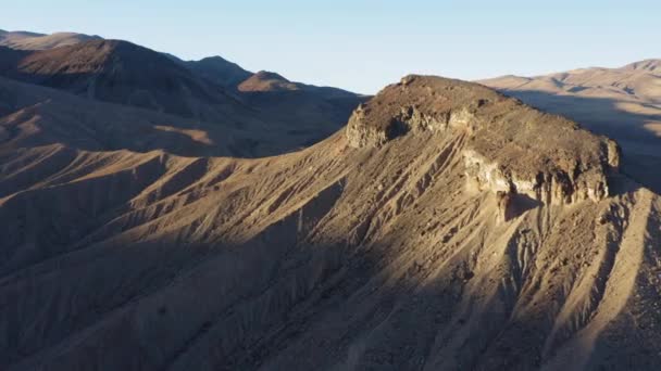 移民の峡谷とカリフォルニア州のデスバレー国立公園に位置する悪魔の中層盆地の山の上を後方に飛ぶドローン — ストック動画