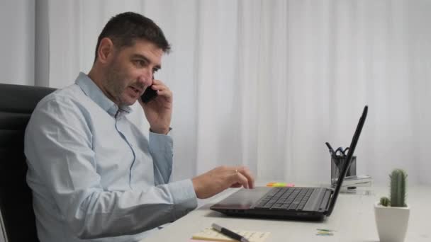 Dolly Portrait ショットビジネス男性は自宅のオフィスから働いています 電話を持つラップトップを入力します — ストック動画