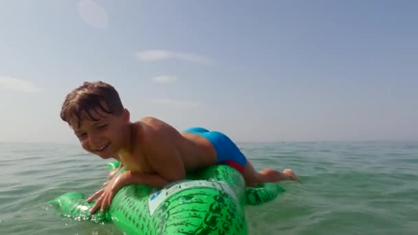 可愛いです面白い子供の男の子楽しいです海の水で膨脹可能なワニに乗るしようとしている 低角度のポルノの — ストック動画
