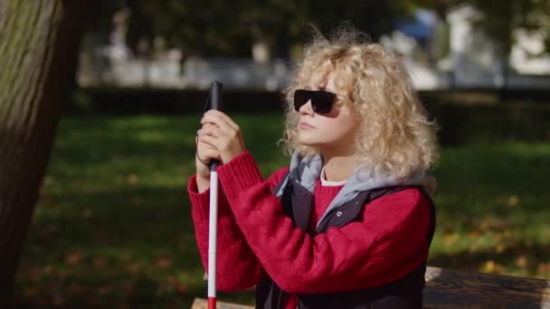 白い杖で公園に座っている黒いサングラスの視覚障害者の女性 終わりだ — ストック動画