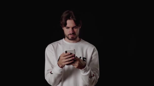 Трендовый Молодой Человек Использующий Раздражающий Телефон Широкий Черный Фон — стоковое видео
