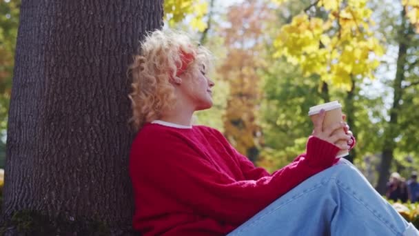 Ung Kvinna Avslappnande Och Sitter Trädet Medan Dricker Varmt Kaffe — Stockvideo