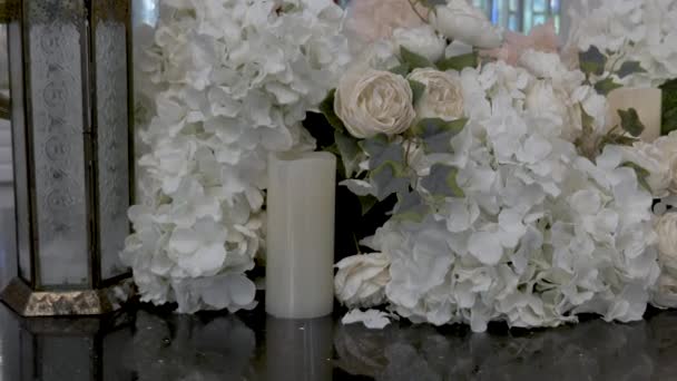 結婚式の機能でテーブルに飾られた美しい白い花やろうそく いつでも女の子のためのロマンチックな贈り物 新婚旅行の結婚式 建物内の居心地の良い暖かい雰囲気 — ストック動画