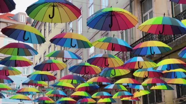 Szivárvány színű esernyők lógnak a rózsaszín utcán Lisszabonban Portugália