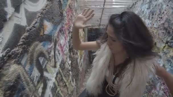 Young Woman Confused Expression Stumbles Stairs Narrow Corridor Covered Graffiti — Stock Video