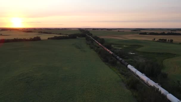 无人机沿着停放着各种谷物的货运列车飞行 五彩缤纷的落日笼罩着乡间草原的风景 从上面看天空的大国 — 图库视频影像
