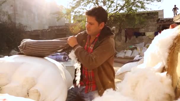 インドの農村のインドの綿市場店で枕を埋める外で働く男の本物の現実の生活シーン 手持ち — ストック動画