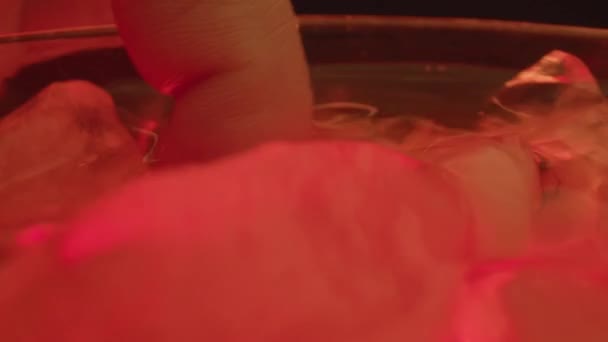 ウイスキーグラスの中で氷と液体を回転させる女性の指のクローズアップ — ストック動画