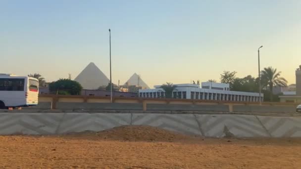 Πλευρική Άποψη Οχήματα Οδηγούν Στο Δρόμο Στην Αίγυπτο Μεγάλες Πυραμίδες — Αρχείο Βίντεο