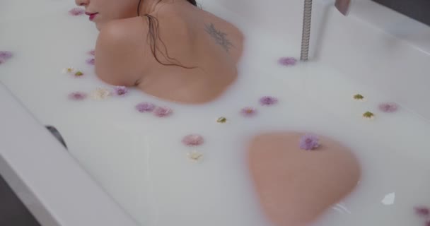 Perfect body woman with her butt cheek visible enjoy milk bath with flowers
