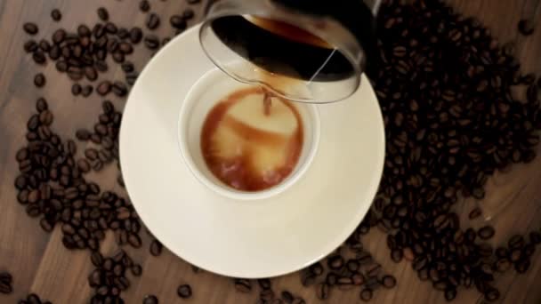 heißer Kaffee, der aus einer Glas-Kaffeekanne in eine Tasse auf einer Tischplatte gegossen wird Video