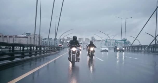 バイカーはそれらに続く車と忙しいぬれた通りでモーターサイクルに乗っています モーターバイクに乗っている人々と霧の通り バイクに乗っているバイカーに安全装置を付けて — ストック動画