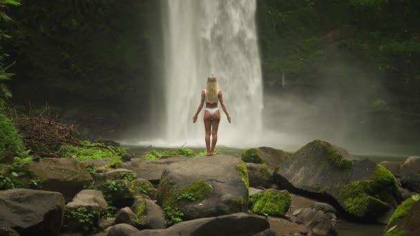 Vrouw Witte Bikini Armen Heffen Begroeten Krachtige Stroom Van Waterval — Stockvideo