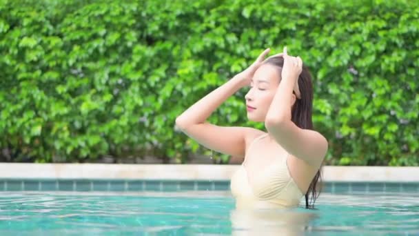 Vášnivá mladá asijská žena doteky a vyhlazuje její mokré vlasy v bazénu v exotickém hotelu se zavřenýma očima, portrét shot