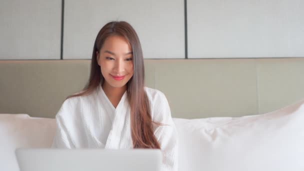 Pretty Asian Kobieta Białym Szlafroku Wpisując Laptopie Siedzi Łóżku Hotelu — Wideo stockowe