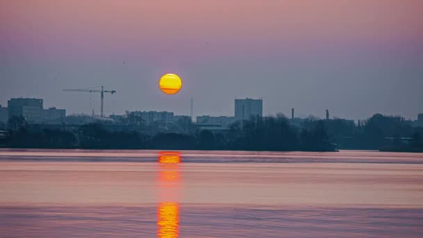 都市スカイラインの日の出シーンの5Kビデオ 川の水に落ちる上昇する太陽の反射と静的なビュー 工場の煙突から煙が出てくる — ストック動画