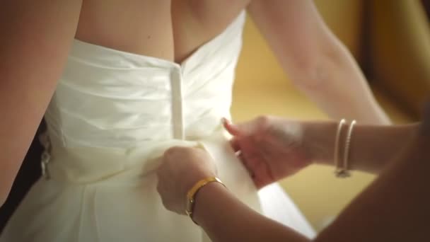 Svatební šaty jsou svázány zezadu jinou ženou