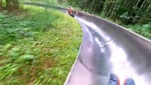 夏のトボガンランに乗っている男のハメ撮り撮影 彼の前には長髪のブロンドの女の子が乗っている 森の中を走るのはとても長いです — ストック動画