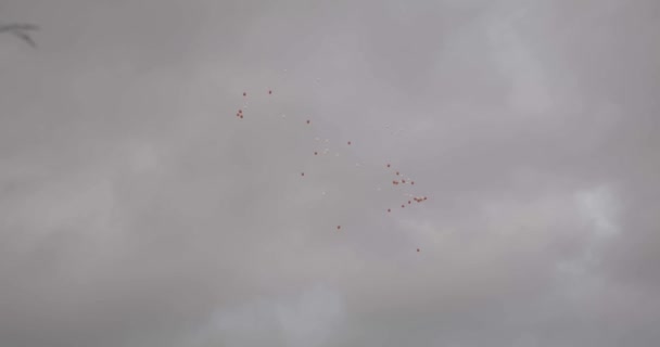 rote und weiße Ballons fliegen in einem bewölkten Himmel