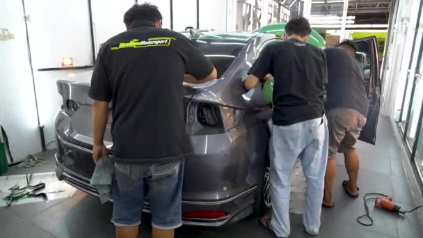 車のサービスステーション従業員は ビニールフィルムステッカーを適用するために清潔で研磨トランク — ストック動画