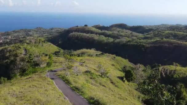 阳光灿烂的日子 一条穿越青山的路 地平线上的海洋 印度尼西亚巴厘 — 图库视频影像