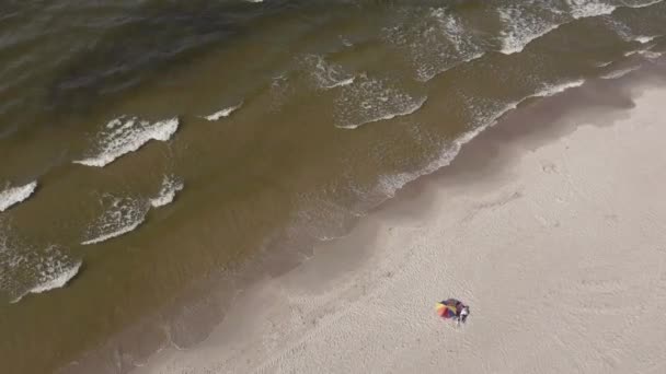 パラソルの下の人々はバルト海のビーチでリラックスしています — ストック動画