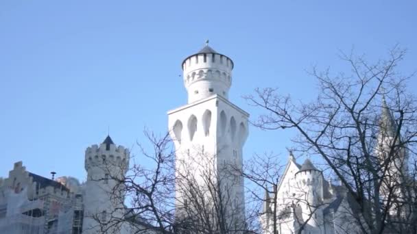 雲のない冷たい青い空の下で ノイシュヴァンシュタイン城の塔の後ろの雪に覆われた山々を明らかにする — ストック動画