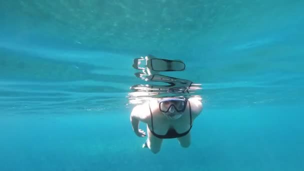 ケファロニアビーチのクリスタルブルーの水の下で女性観光客がカメラに向かって泳ぐ — ストック動画