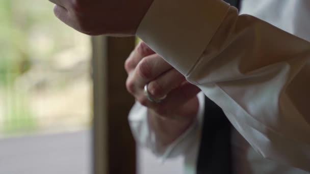 Ženich v bílých šatech košile nastavení upevnění jeho rukávu manžetové knoflíčky.