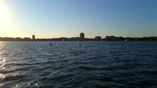 在明尼苏达州明尼阿波利斯市Bde Maka Ska湖畔的一个阳光明媚的夏日午后 一群朋友在一块木板上划桨 — 图库视频影像