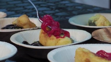 Şef soğan soslu ve kırmızı soslu bir tabakta kızarmış balık ve mürekkepbalıklı spagetti.