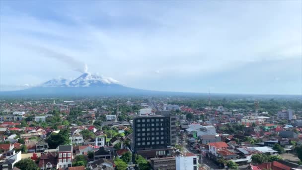 背景の山と澄んだ青い空を背景に 上からのヨガジャカルタ市の空中パンショット — ストック動画