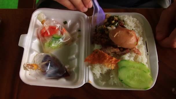 フードデリバリーサービスによる発泡スチロール容器に詰められたカウサッチクルックと呼ばれる伝統的な食品を食べる男のトップビュー — ストック動画