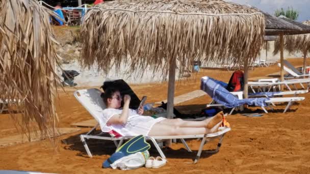 Turista Feminina Usando Smartphone Enquanto Relaxa Espreguiçadeira Megas Lakkos Beach — Vídeo de Stock