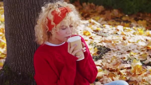 Kobieta Pijąca Gorącą Kawę Świeżym Powietrzu Siedząc Jesienią Obok Drzewa — Wideo stockowe