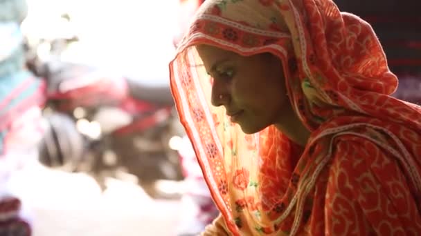インド ラジャスタン州のショップで仕事の縫製毛布でカラフルなオレンジ色のサリーを持つ美しい本物のインドの女性 手持ち — ストック動画