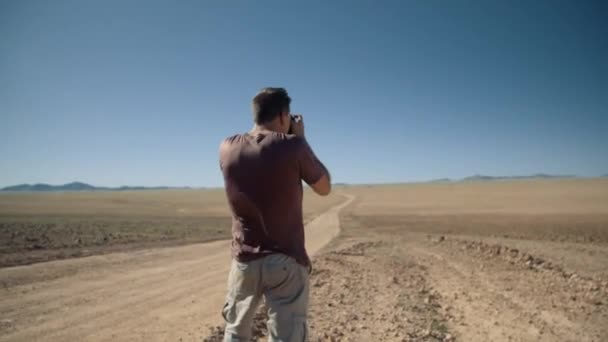 Ruční záběr fotografa turisty fotit pouštní silnici kontrolu jeho fotografie v Africe.