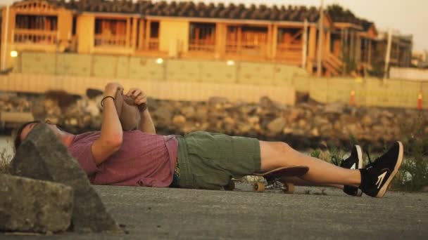 Skateboarder Met Lang Krullend Haar Staat Van Grond Trekt Zijn — Stockvideo